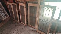 Five wood framed leaded glass cabinet doors leaning against wall