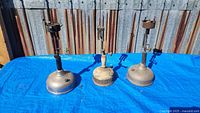 Three Coleman lantern table lamp bases on blue tarp