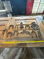 All eleven antique door knocker pieces laid out next to a measuring tape