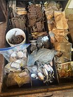Drawer showing mixed antique hardware including bagged porcelain knobs, chrome pulls, brass latches, ornate hinges