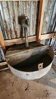 Front view of galvanized livestock water trough mounted against wall