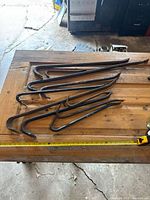 All nine crowbars laid flat with tape measure for scale