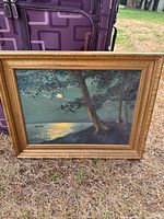Full view of framed E.E. Howe oil painting leaning against luggage
