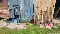 Full lot of garden tools leaning against shed