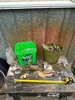Overall lot on table: bucket, plastic tub, scattered pulls and tape measure for scale