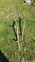 Two wooden scythes laid on grass full view