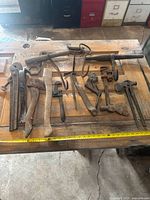 Assorted vintage hand tools laid out on workbench with measuring tape for scale