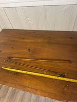 Two wooden violin bows on table with measuring tape