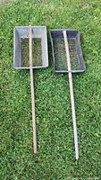Both long-handled metal sifting scoops on grass