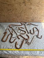 Full lot of 11 rusted steel S hooks on fabric surface