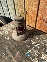 Front view of metal lamp with red glass lens and wire guard