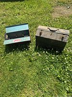 Two toolboxes side by side on grass, one open showing Homak badge