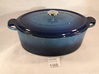 Front view of blue oval cast iron French oven with lid and handles.