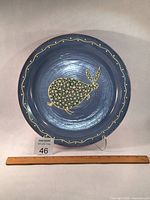 Full view of the round ceramic platter showing the bunny motif and slip work decoration on blue-grey glaze.