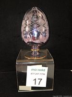 Front view of the light blue/mauve blown glass egg with etched geometric patterns and gold trim on a clear pedestal base