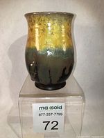 Front view of the porcelain vase showing yellow crystalline glaze with floral motifs and dark base.