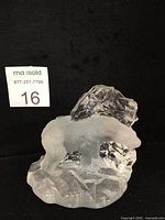 Front and side views of frosted and clear crystal polar bear figurine with textured base and faceted background element on black background.