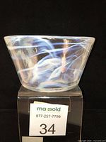 Front left side view of opalescent glass bowl showing irregular shape and blue-white swirl pattern.