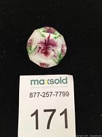 Photo of the brooch on a black background showing the carved orchid design and faceted lucite surface