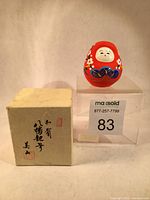 Doll and original box placed side by side on display stand, showing overall condition and size comparison