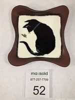 Top view of red stoneware trinket dish with black cat and bumblebee image in center.