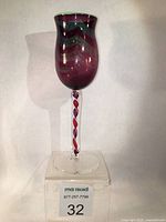 Front view of the blown glass goblet showing its metallic purple bowl with chevron pattern and pink/purple twisted cane stem.