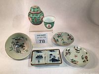 Wide photo showing all six miniature Chinese porcelain items including turquoise jar and cup, two small famille rose saucers, rectangular sauce dish, and celadon bowl.