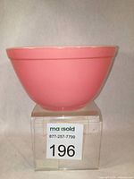 Front angled view of vintage pink Pyrex mixing bowl showing glossy bright flamingo pink finish and bowl shape.