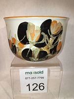 Front and angled view of the ceramic bowl showing the painted floral abstract pattern in black, orange, gold and beige with an orange rim.