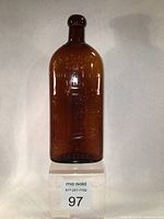 Front view of amber patent medicine bottle showing embossed text and image of bank safe