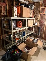 Photo showing shelves with Halloween decorations and 3 boxes on floor containing more items.