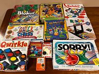 Full overview of the twelve board and card games arranged on table, showing box art and titles.