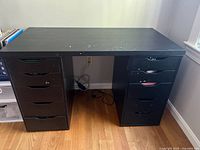Front view of the black/brown desk with 10 drawers, showing paint splatters and wear on top surface.