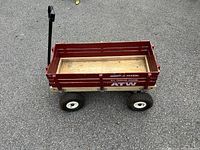 Radio Flyer All Terrain Kid Wagon with wooden base and red painted metal sides; four rubber tires; black handle.