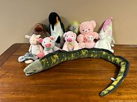 Full view of all 12 plush stuffed toys arranged on a table, showing variety of animals and sizes.