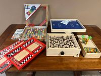 Lot of wooden tabletop games including ColorKu, Fastrack, Labyrinth, wooden xylophone and game boards on table.