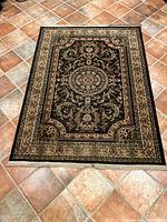 Full view of the Oriental Weavers Florent Nandrin Black area rug showing its intricate pattern, color scheme, and size on a tiled floor.