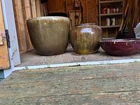 Three ceramic planters in a row with varying sizes and glazes.