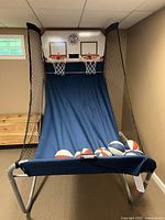 Assembled Pop-A-Shot game with dual hoops, electronic scoreboard, blue nylon ramp and seven red-white-blue basketballs.
