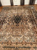 Full view of the traditional area rug laid out on wooden floor showing overall design and distressed look.