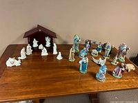 Full view of both nativity sets, showing white set with wooden stable and colorful set with various figurines
