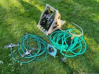 Overview of hoses, hose reel, and sprinklers laid on grass.