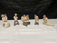 Front view of all five Willow Tree figurines displayed in a row on a white cloth against black background.