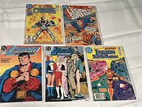 Six DC comic book issues displayed neatly on a white surface, featuring titles Tales of the Titans Mini Series and various Legion of Superheroes issues.