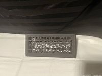 Single rectangular cast iron floor register with ornate cut-out design