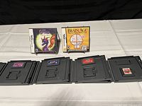 Nintendo DS game cartridges displayed on a white cloth with black backdrop. Two games have visible box covers: Spyro and Brain Age. Four cartridges are loose and visible with label colors and titles.