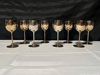 Set of eight small vintage goblets, brass plated with silver plated base, arranged in two rows.