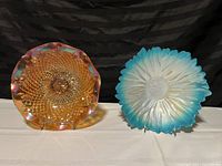 Blue and white flower-shaped glass bowl with petal details and textured center, displayed next to the carnival bowl.