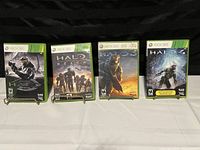 Four Xbox 360 Halo game cases displayed in a row, showing front covers including Halo 3, Halo Reach, Halo 3 ODST, and Halo 4.