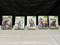 Photo showing five Xbox 360 game cases arranged in a row: Watch Dogs, Red Faction Guerrilla, Call of Duty Black Ops II, Battlefield 3, and Call of Duty Modern Warfare 3.
